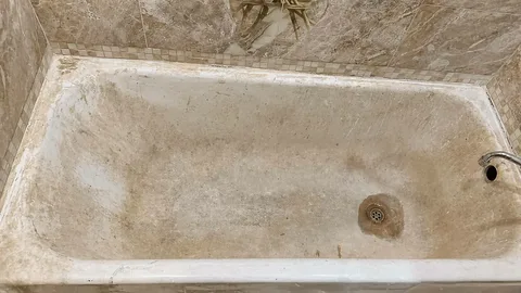 Bathtub before refinishing, showing a stained and worn surface